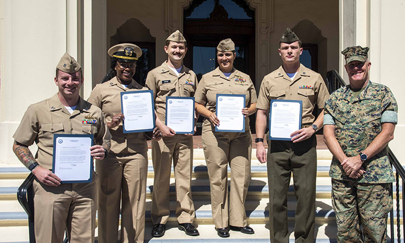 The latest cohort of Naval Information Warfare Center Pacific Fellows and Naval Warfare Studies Institute Director on the steps of Herrmann Hall at NPS. 